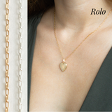 A gold heart locket with a gold chain on a model wearing a green top.