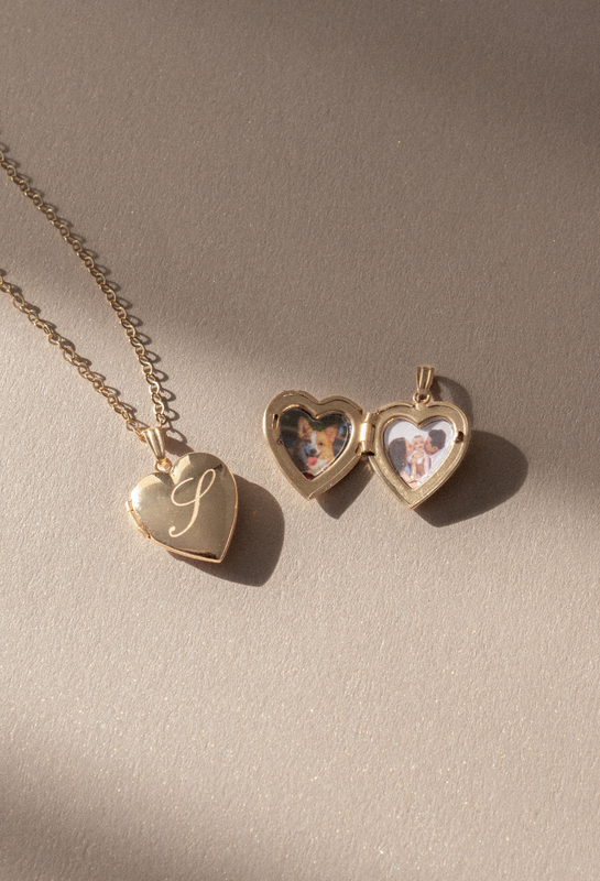 Gold fill heart lockets in a flat lay. One is closed with an initial on the front and another is open to show the photos.
